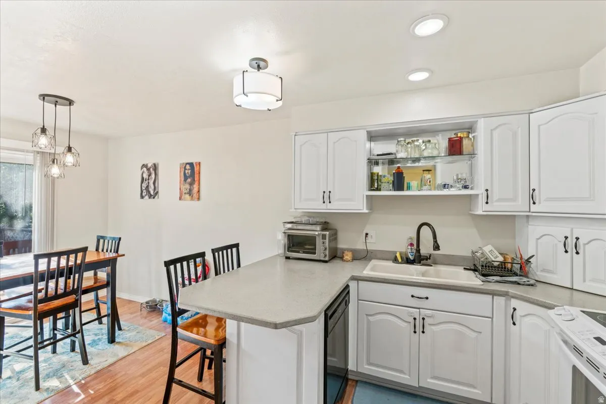 Kitchen with white cabinets, a peninsula, white range with electric cooktop, and light wood-style flooring