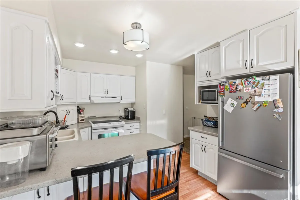 Kitchen featuring stainless steel appliances, white cabinetry, a peninsula, a kitchen breakfast bar, and recessed lighting