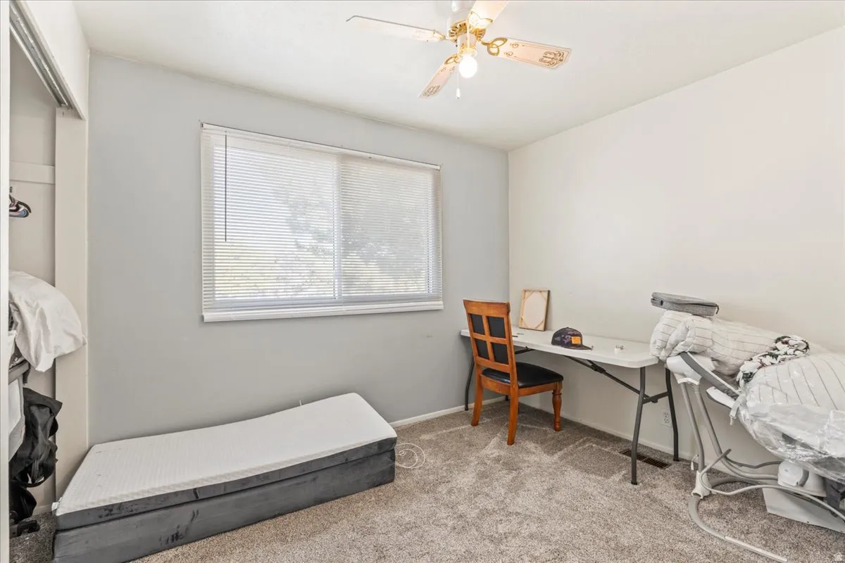 Home office with light carpet and ceiling fan