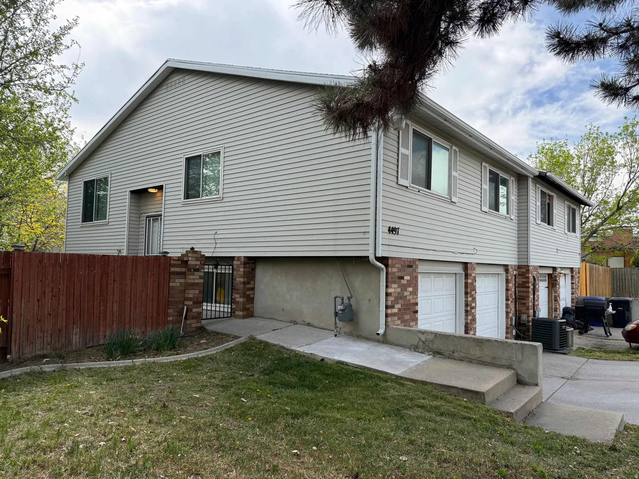 View of home's exterior featuring an attached garage, brick siding, and a gate