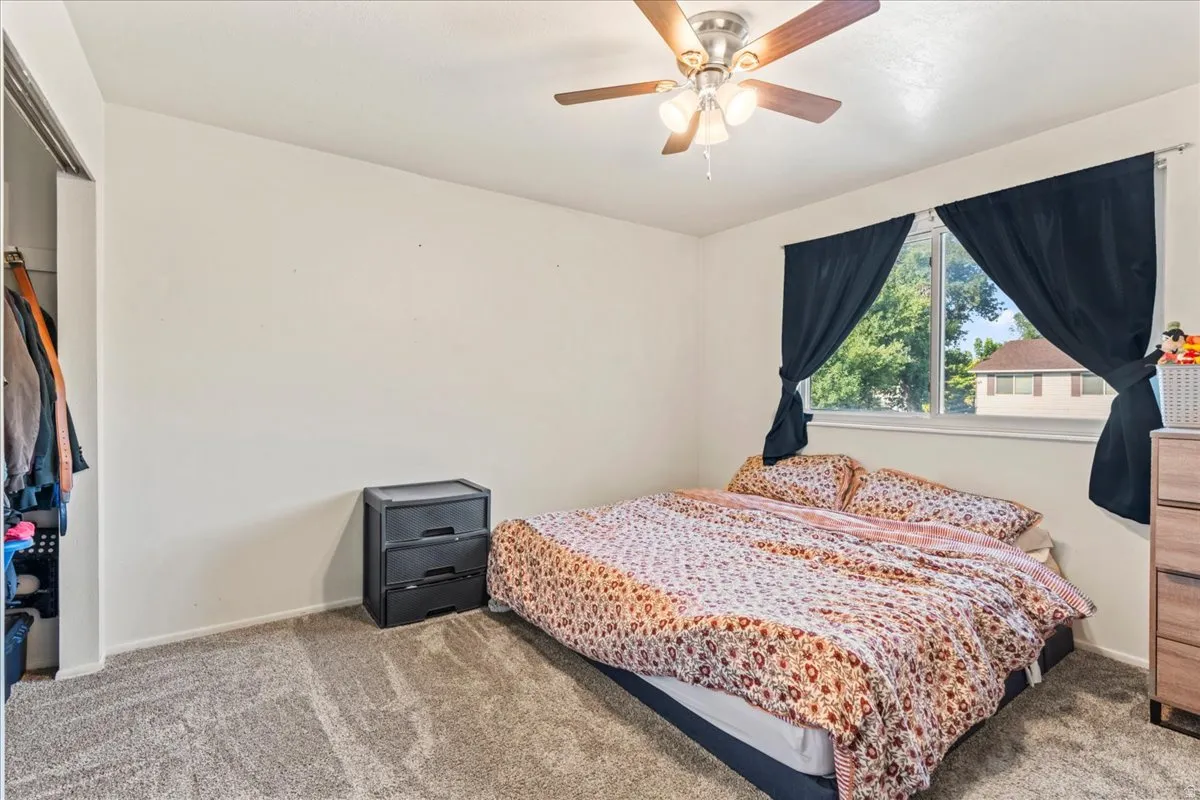 Bedroom with light carpet, a closet, and ceiling fan