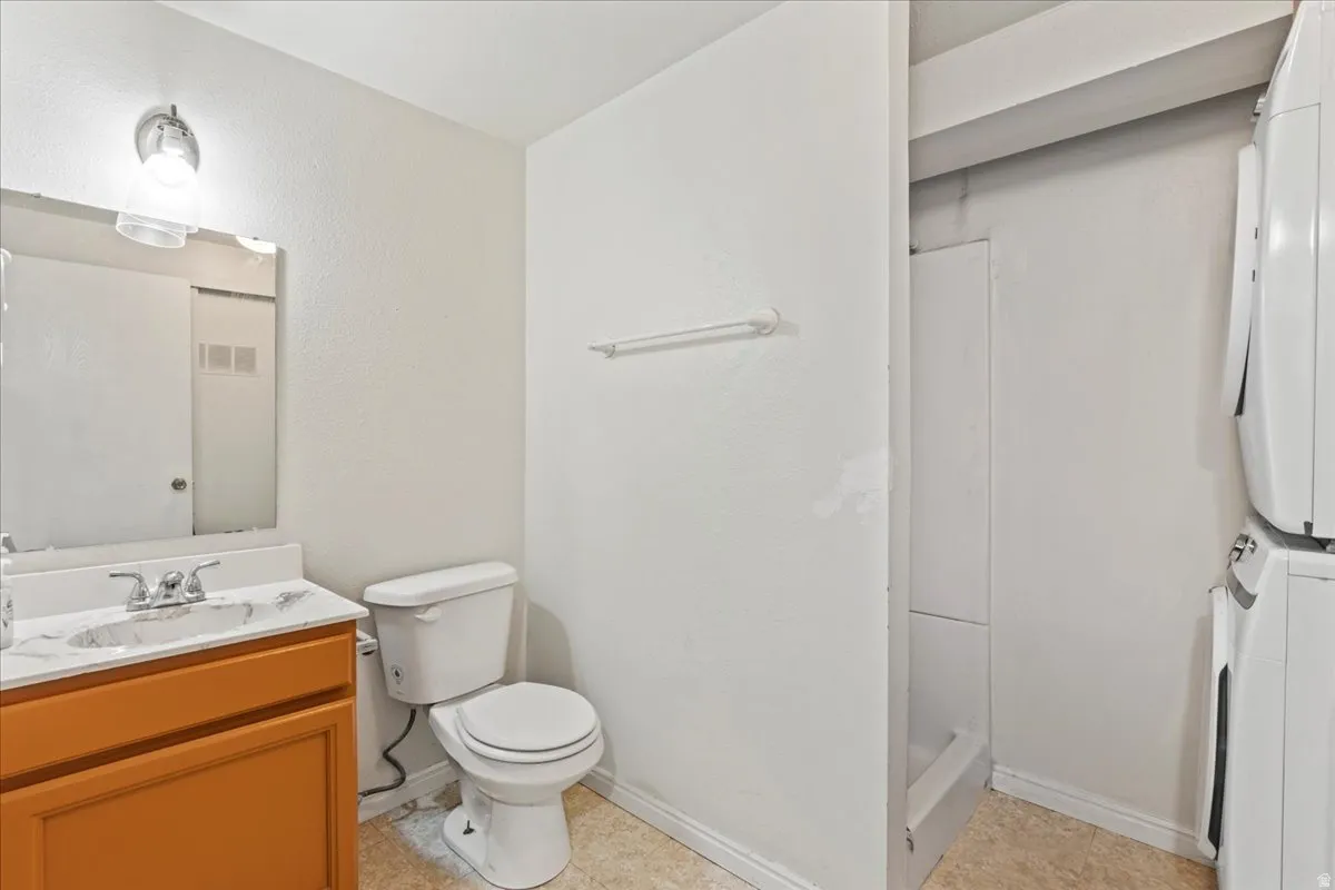 Full bath featuring vanity, a shower stall, stacked washing machine and dryer, and electric panel