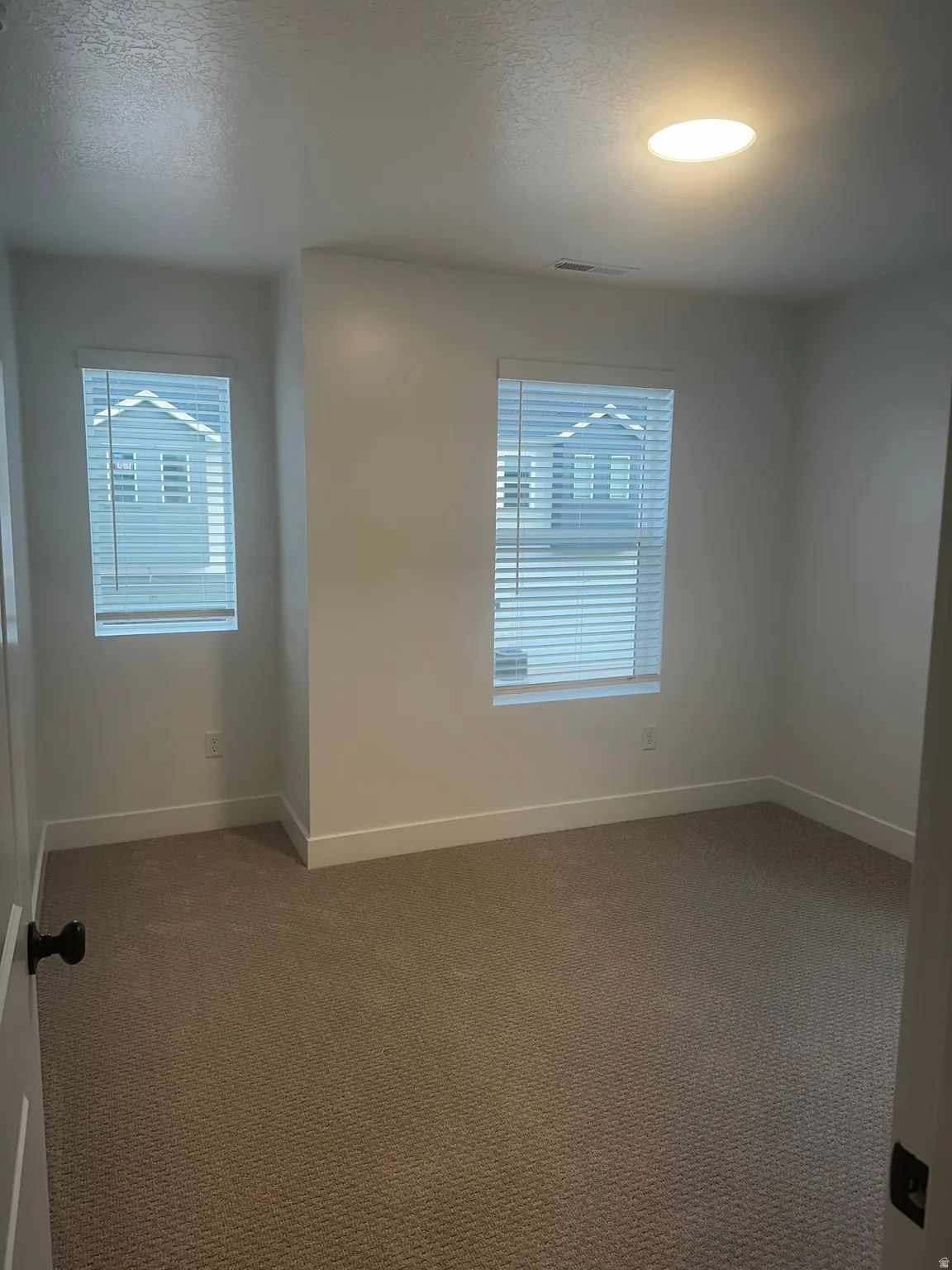 Empty room with dark colored carpet and a textured ceiling