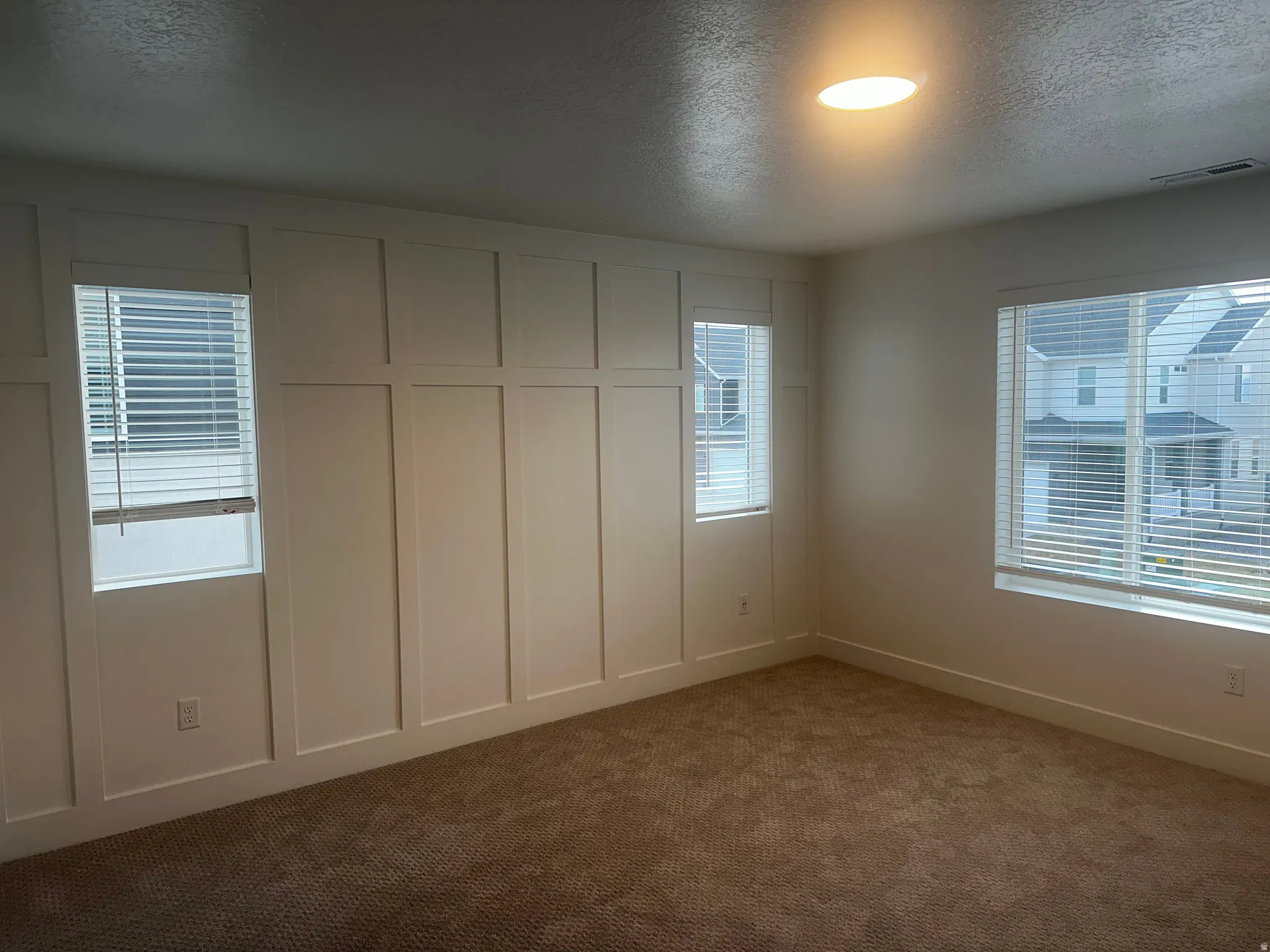 Unfurnished bedroom featuring a textured ceiling, dark carpet, and a decorative wall