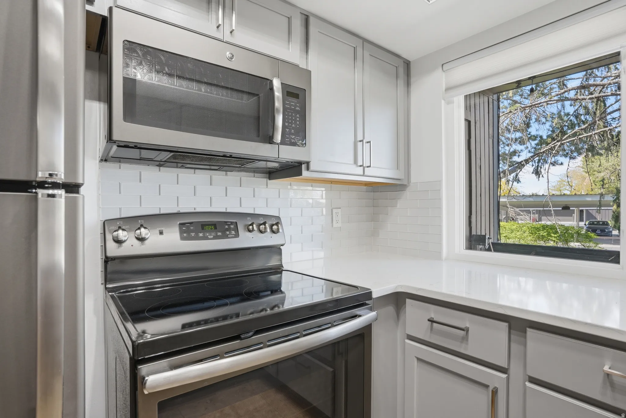 Kitchen featuring stainless steel appliances, backsplash, and gray cabinets, updated! Quartz counters!!!