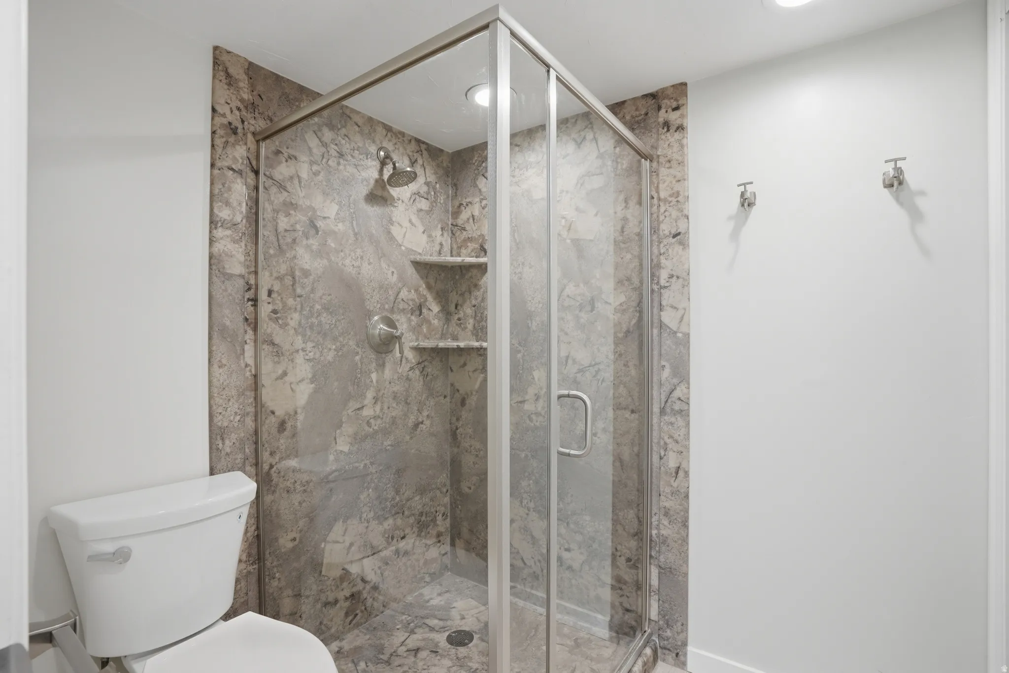 Bathroom with toilet and a marble finish shower, updated