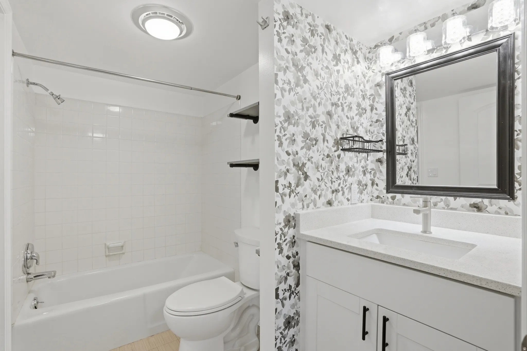 Bathroom featuring vanity, wallpapered walls, and shower / tub combination