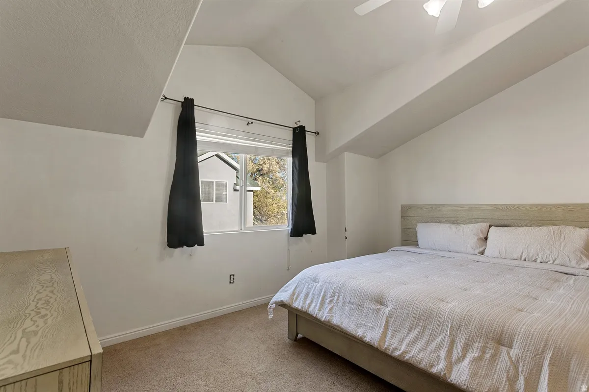 Bedroom with light carpet, lofted ceiling, and a ceiling fan