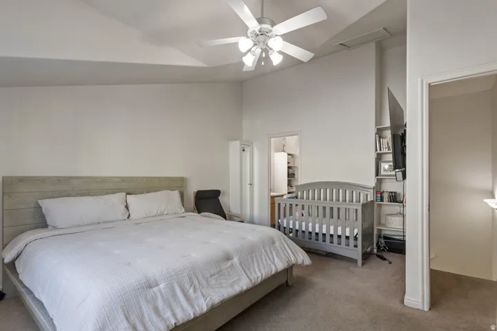 Bedroom featuring vaulted ceiling, carpet flooring, and a ceiling fan