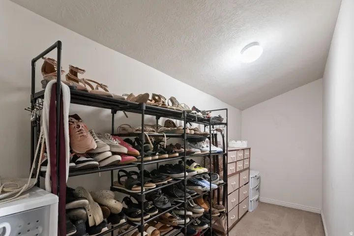 Walk in closet with lofted ceiling and light carpet
