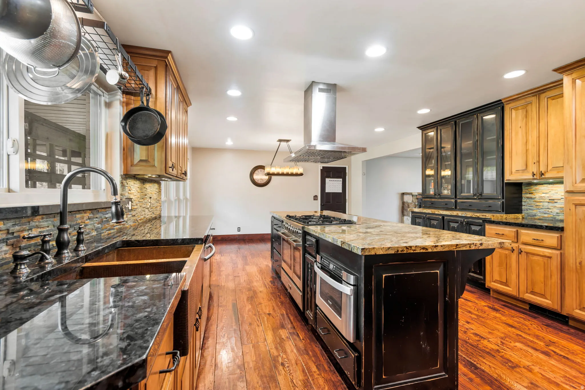 Two tone kitchen featuring decorative backsplash, island range hood, two tone color scheme, a kitchen island, and dark wood finished floors
