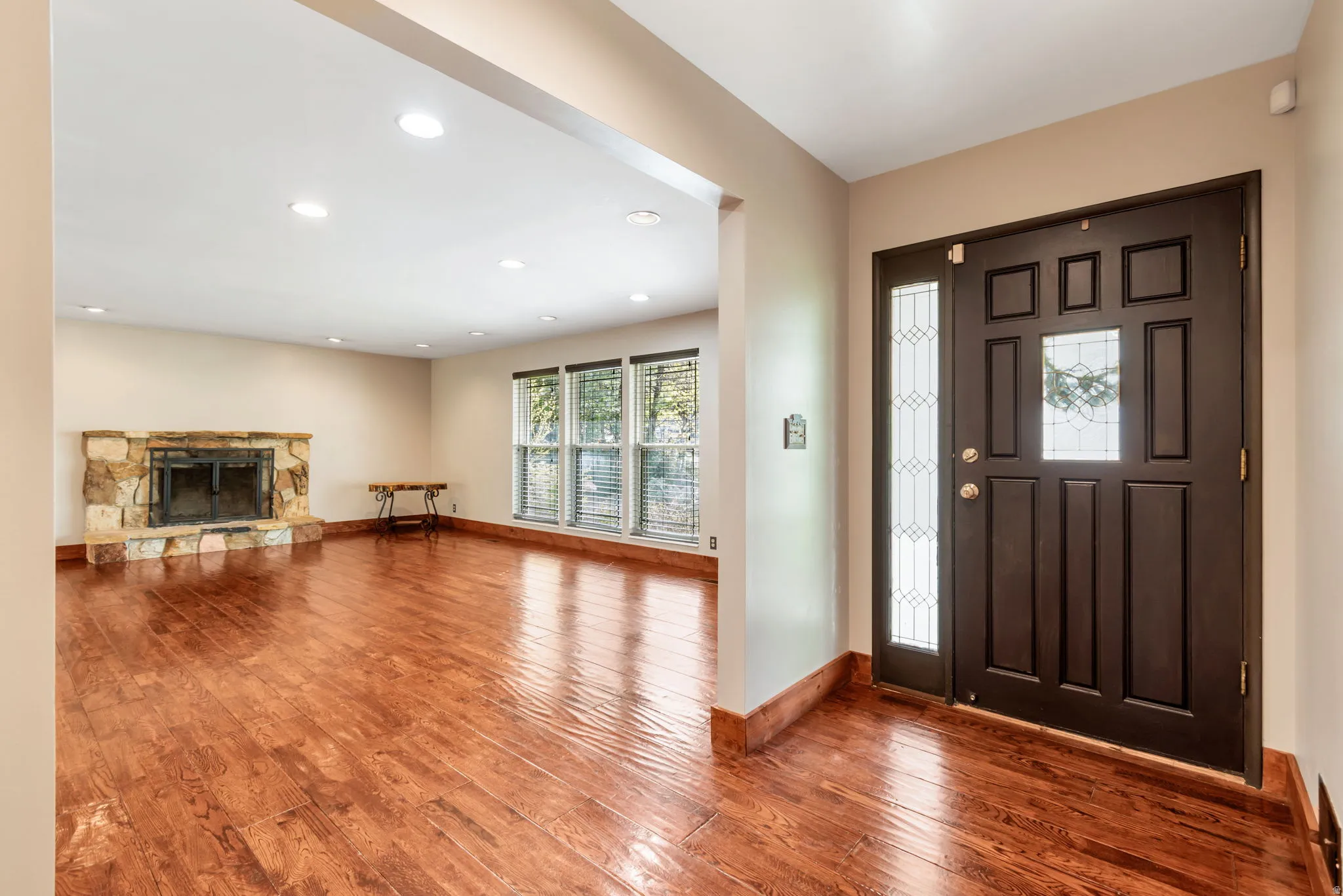 Foyer with dark wood-style floors, recessed lighting, and a stone fireplace