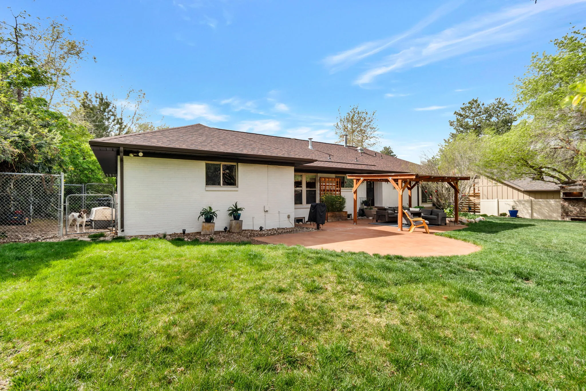 Back of house featuring a fenced backyard, a gate, brick siding, a patio area, and roof with shingles