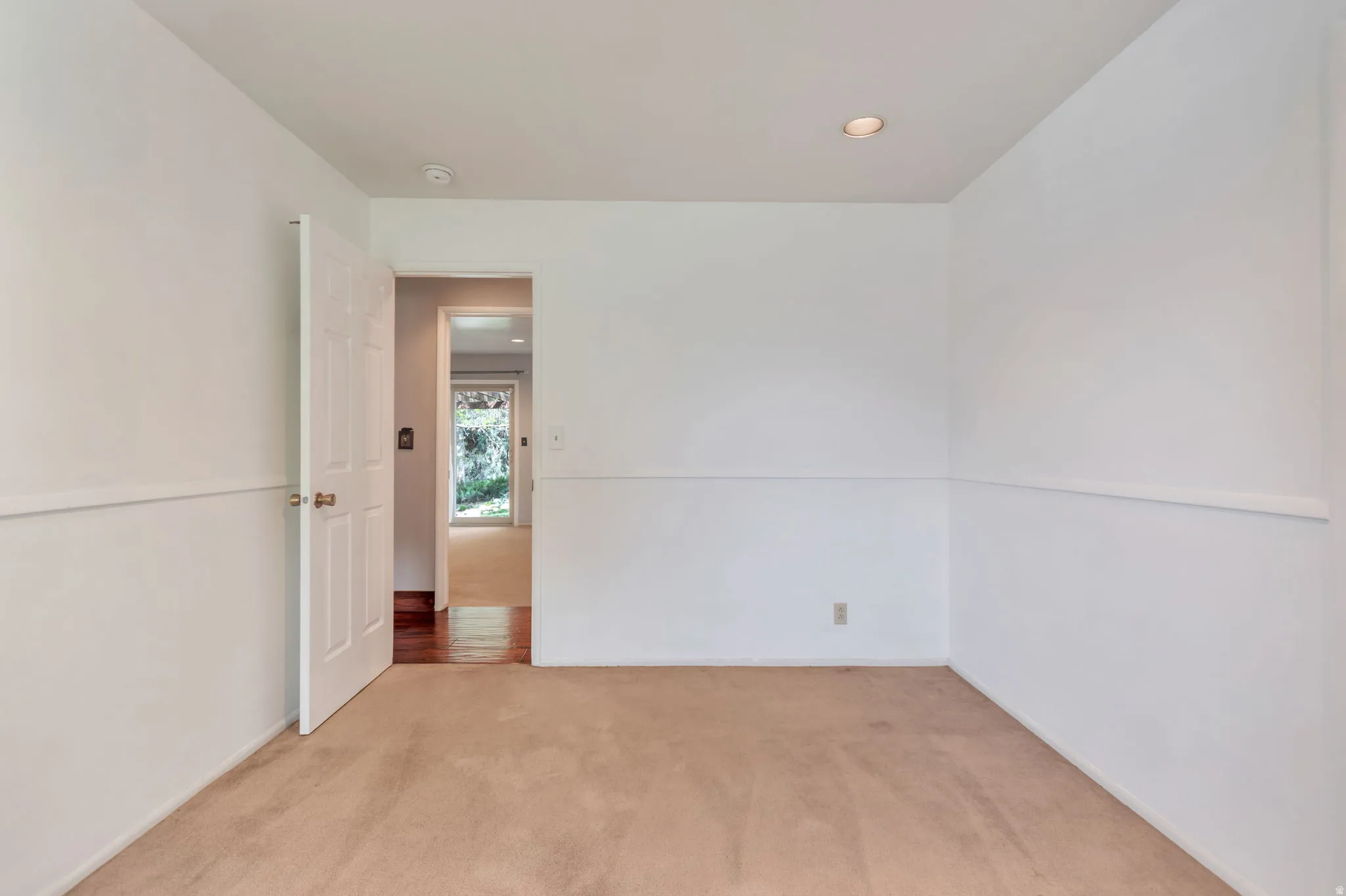 Empty room with light colored carpet and recessed lighting