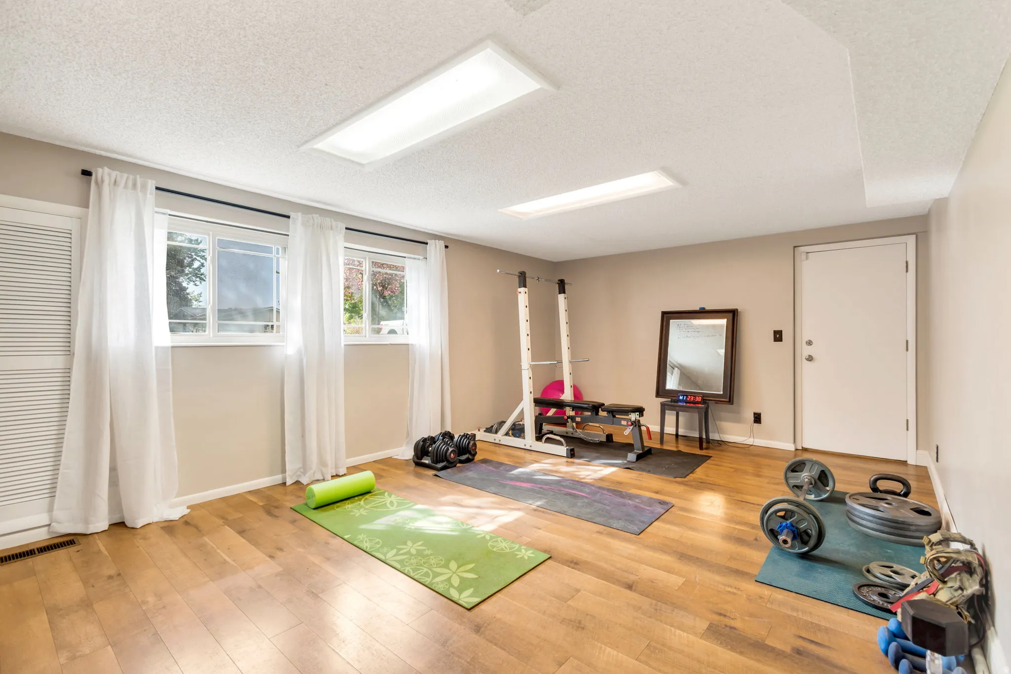 Workout area with light wood-style floors and a textured ceiling