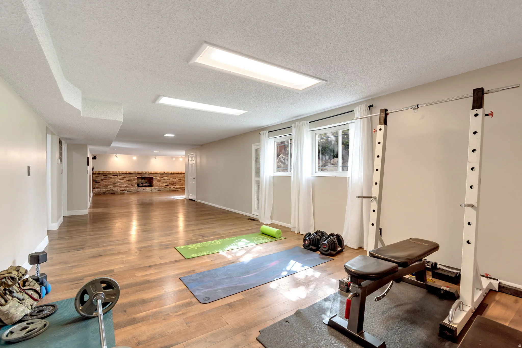 Exercise room with brick wall, wood finished floors, and a textured ceiling