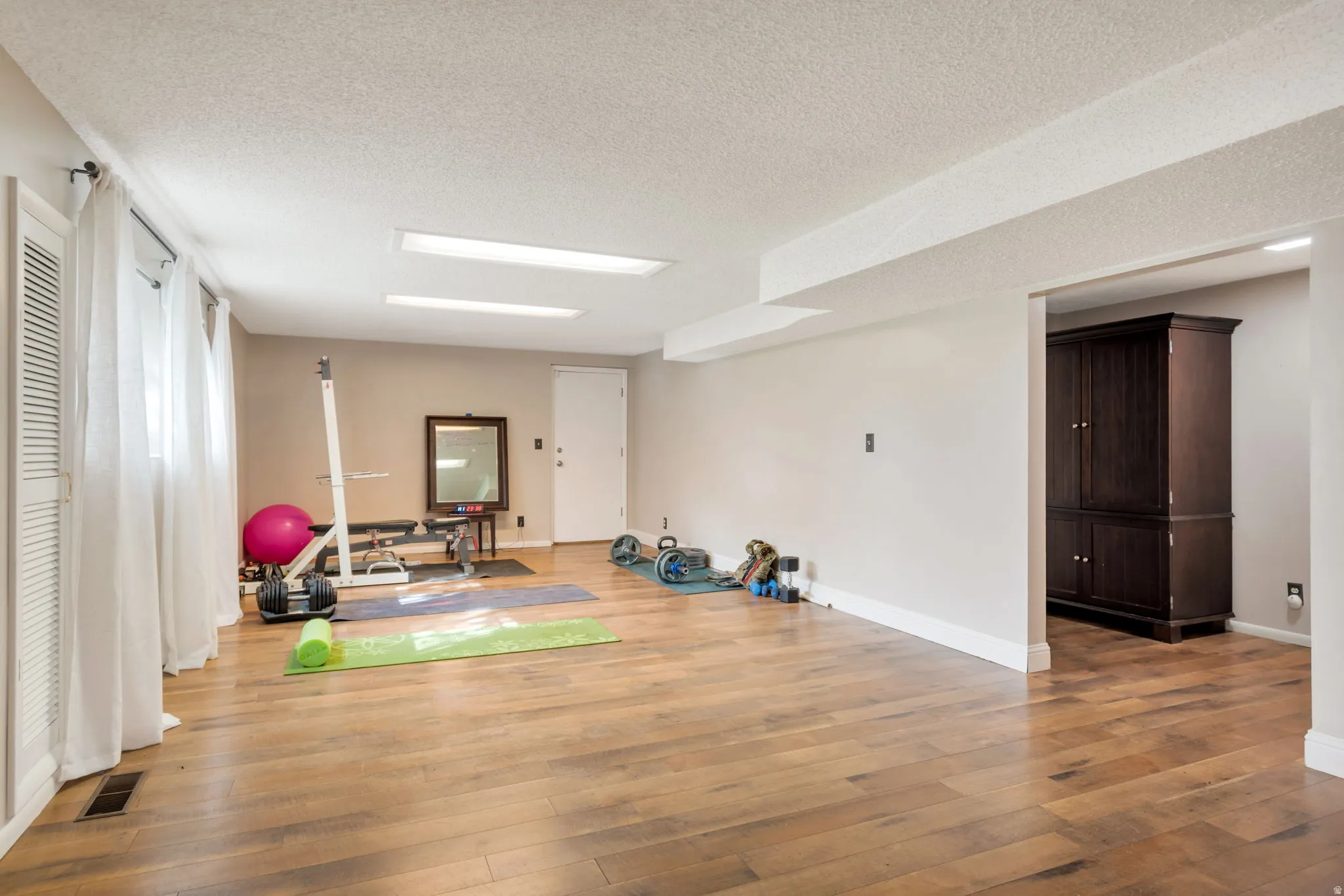 Exercise area featuring light wood-style floors and a textured ceiling