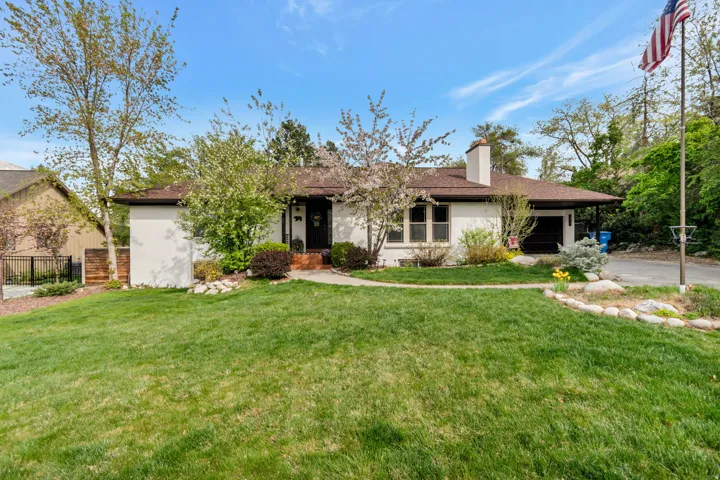 View of front of house featuring a garage, a chimney, stucco siding, and driveway