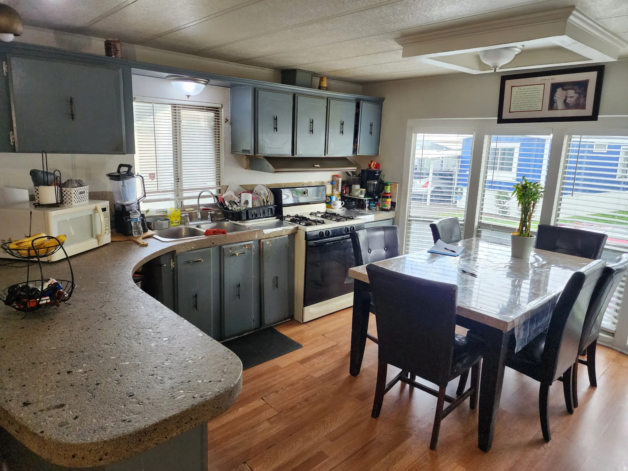 Kitchen with gray cabinetry, gas range, white microwave, and light wood-style floors
