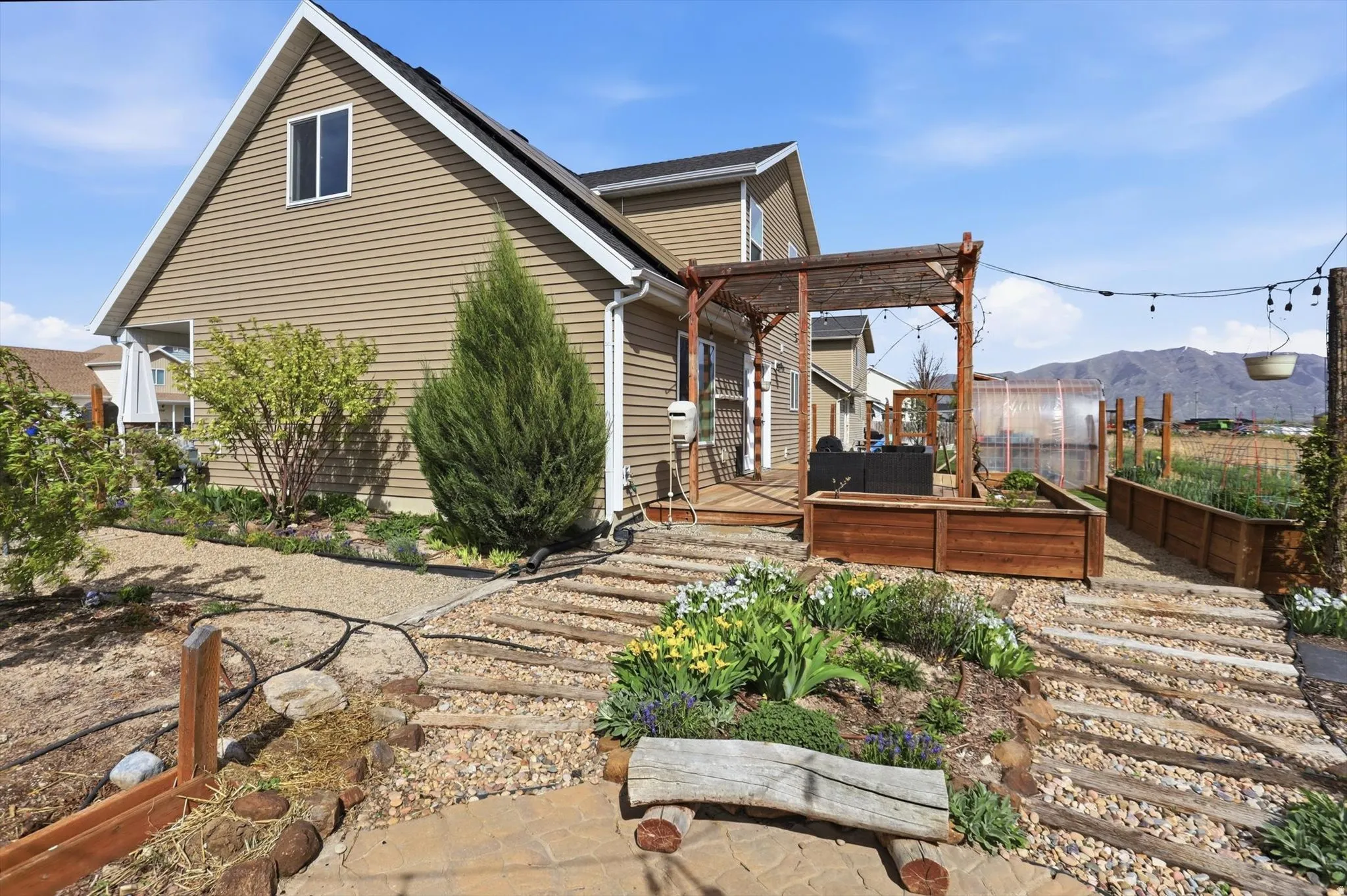 Back of house with a deck with mountain view and a garden