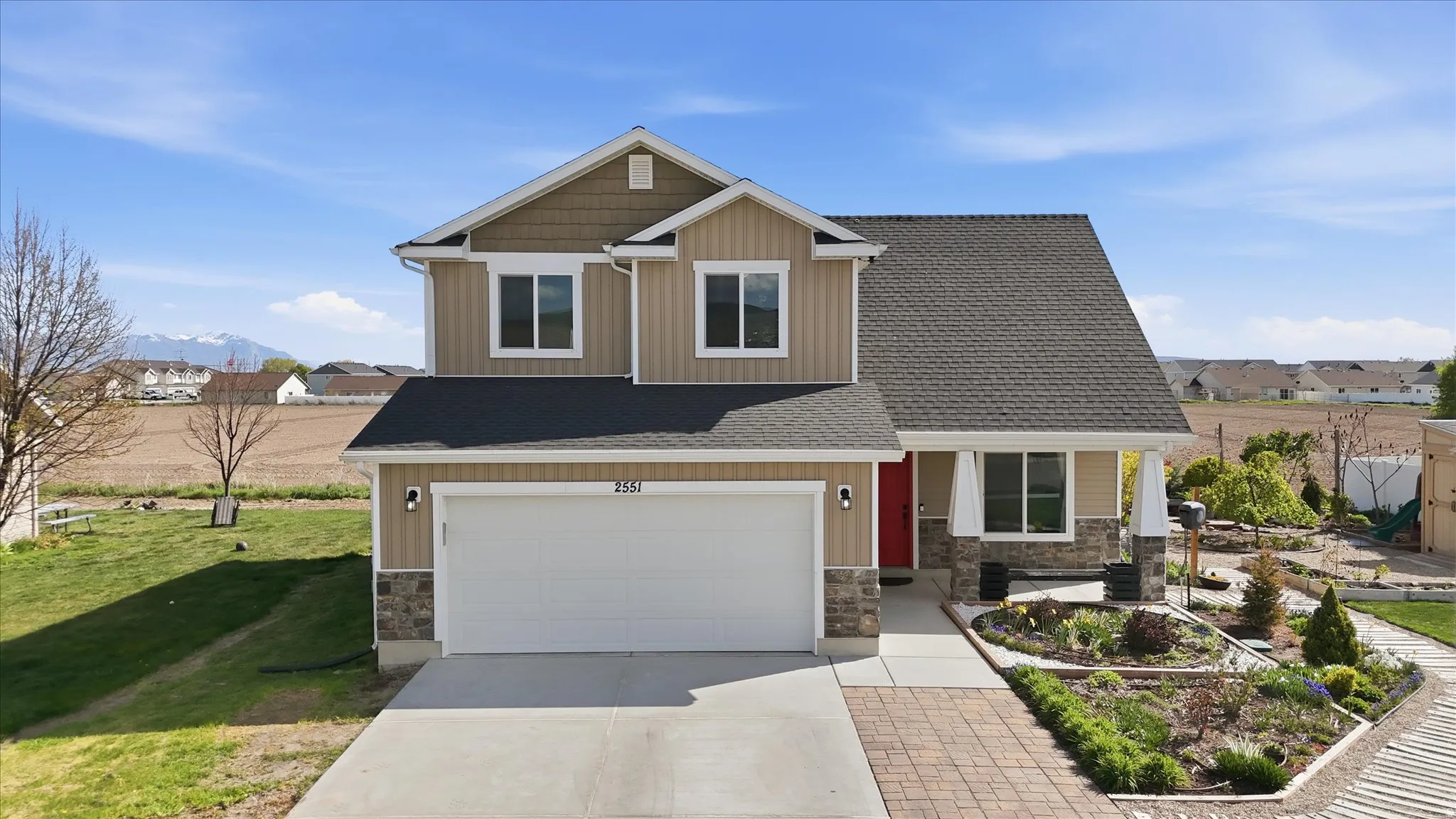 Craftsman house featuring driveway, a residential view, stone siding, a garage, and roof with shingles