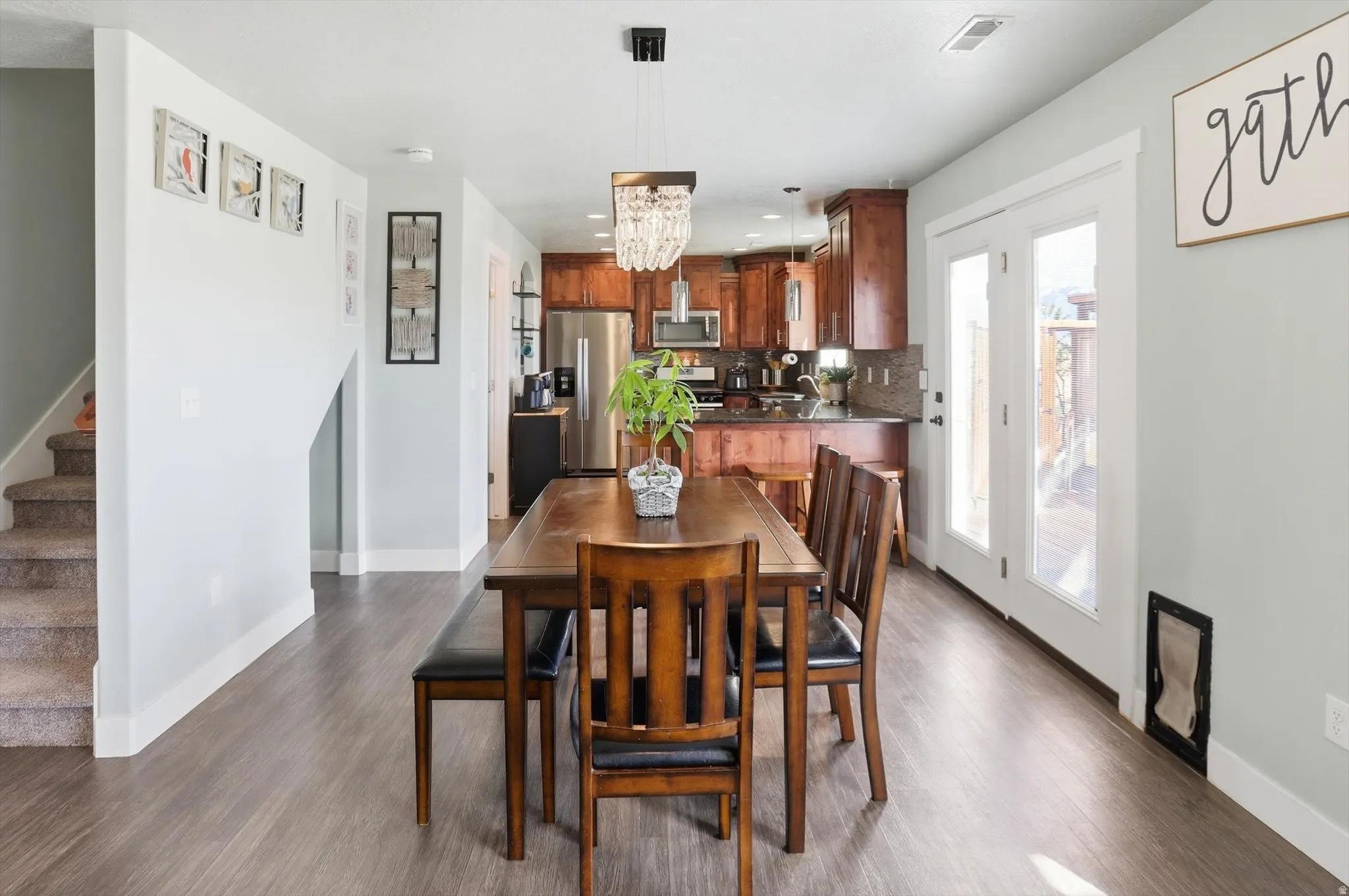 Dining room with dark wood-style flooring and suspended lighting