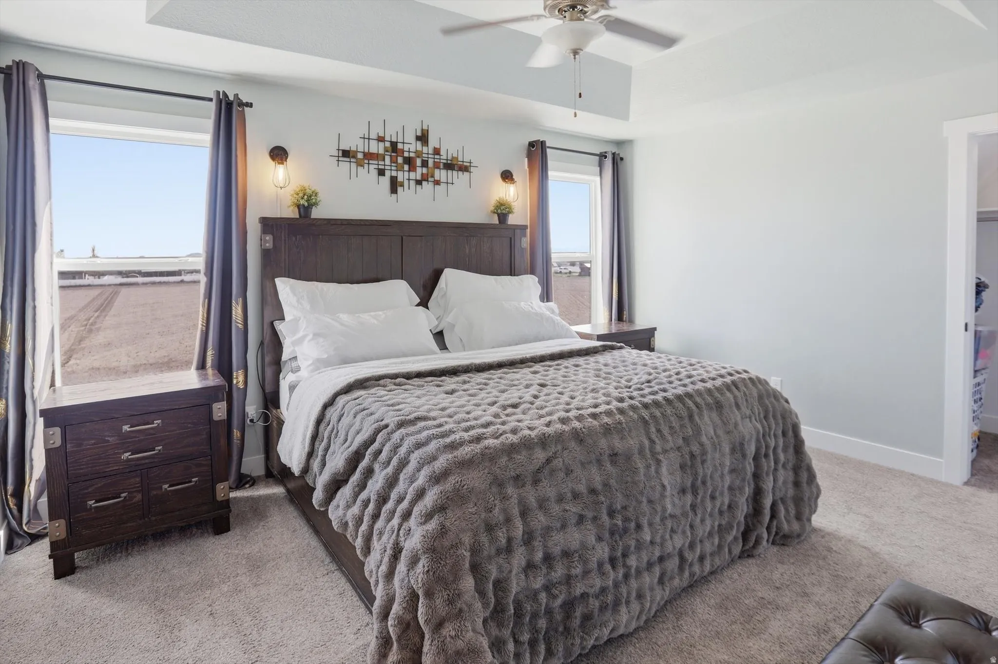 Bedroom with light carpet, a tray ceiling, and a ceiling fan