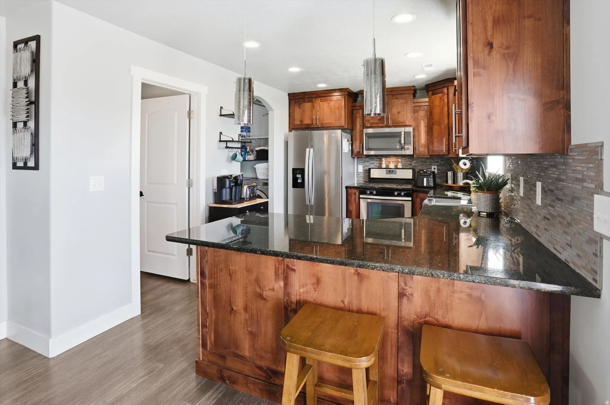 Kitchen featuring a peninsula, dark stone counters, a breakfast bar, stainless steel appliances, and tasteful backsplash