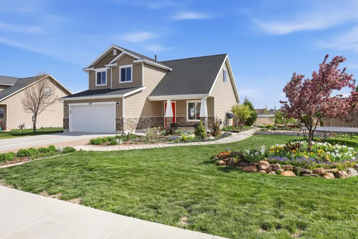 Craftsman house featuring covered porch, a front yard, a garage, stone siding, and driveway