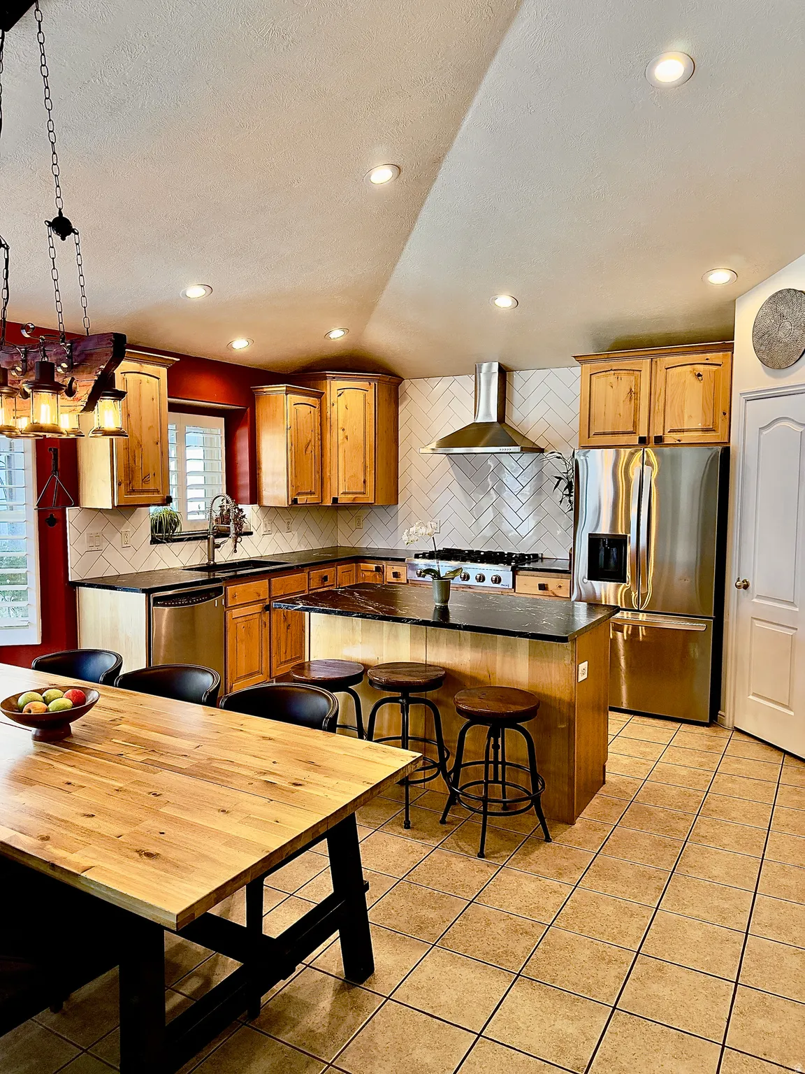 Kitchen with a breakfast bar, stainless steel appliances, a kitchen island, light tile patterned flooring, and a textured ceiling
