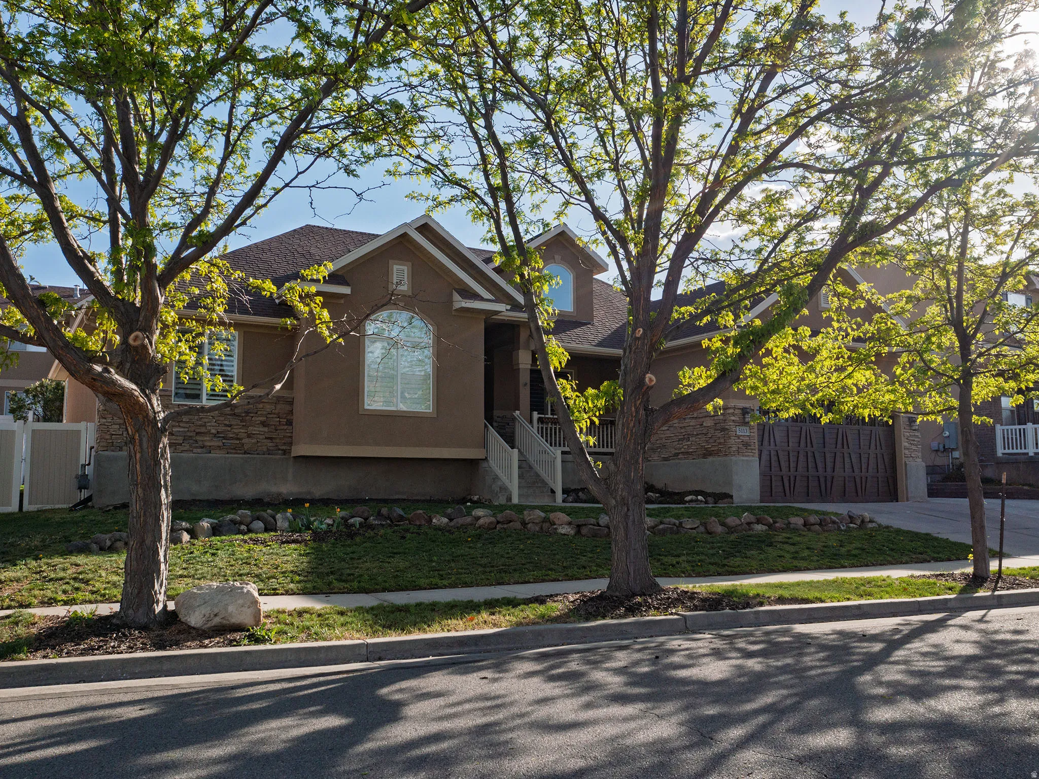 Traditional home featuring stucco siding, driveway, a shingled roof, and stone siding