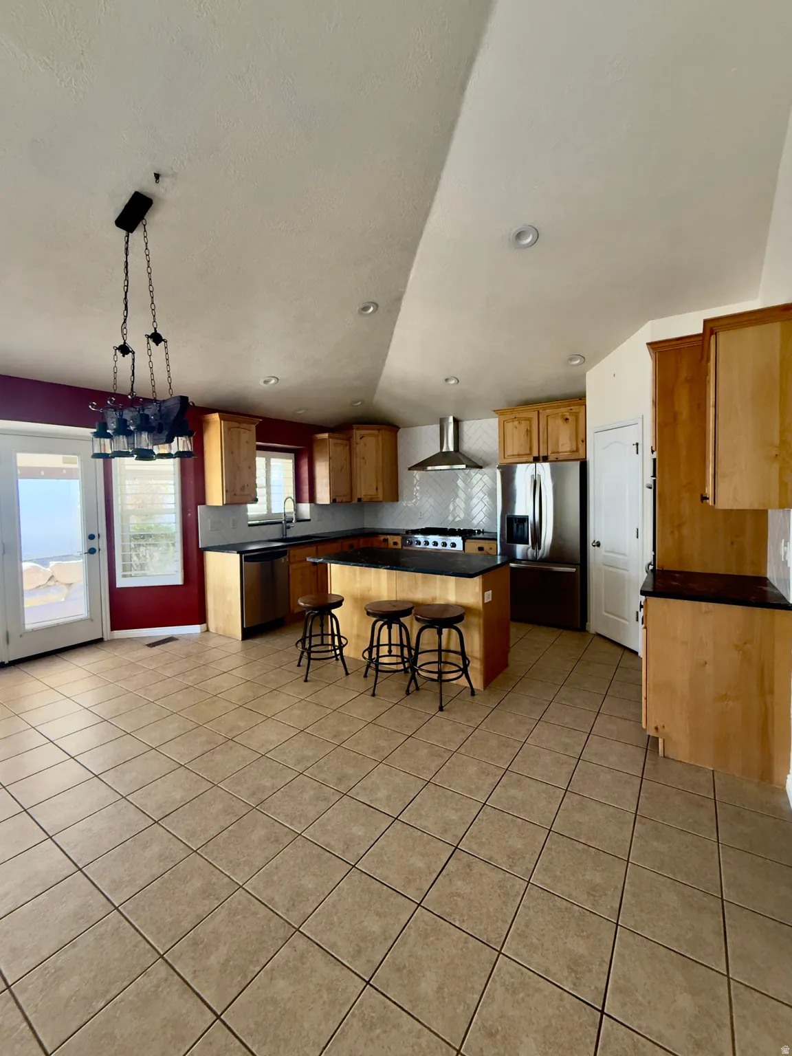 Open-concept kitchen and dining area featuring light wood cabinetry, dark countertops, and stainless steel appliances