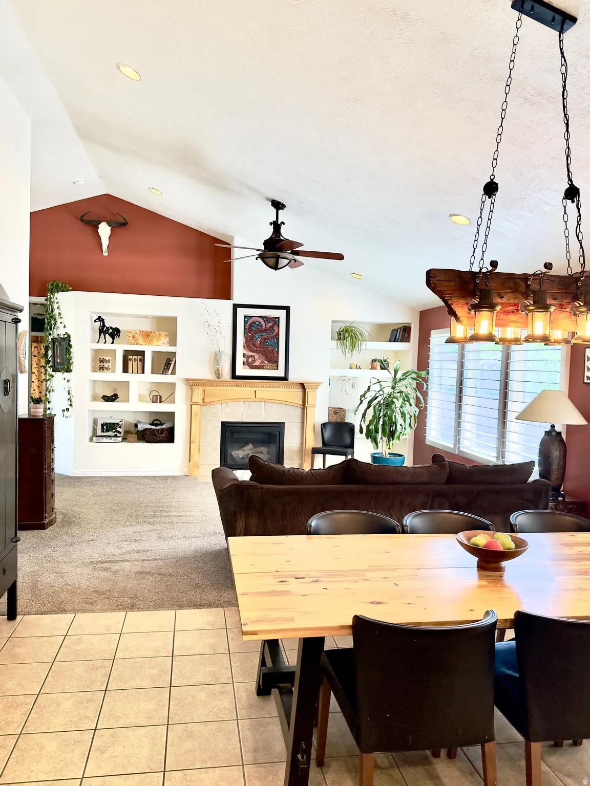 Dining space with a fireplace, light tile patterned floors, light carpet, and ceiling fan