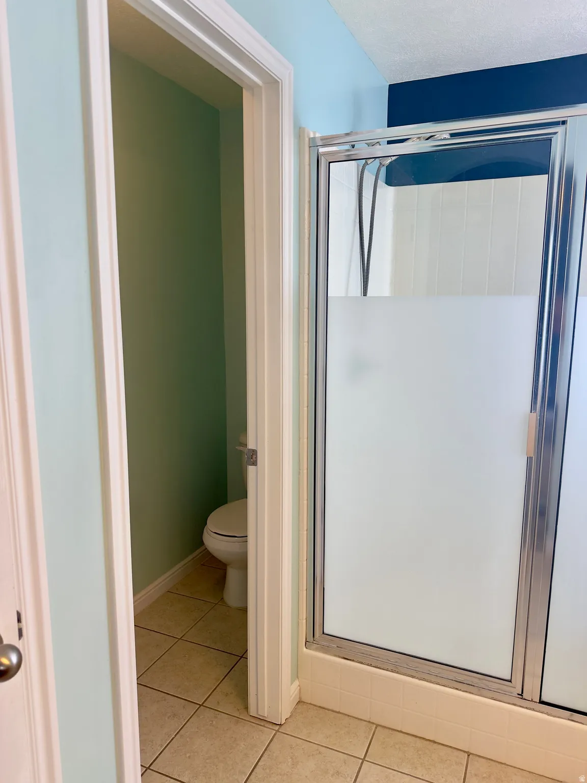 Shower enclosure with frosted glass panels, chrome framing, and white tiled base