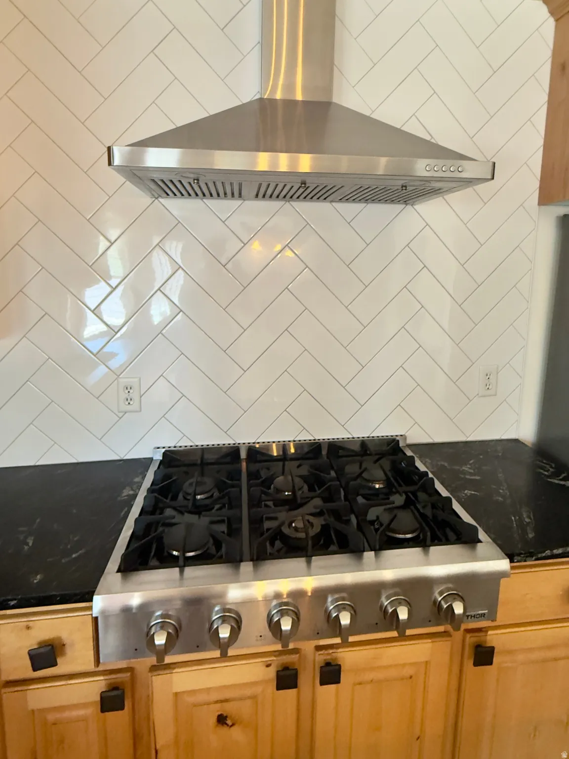 Stainless steel professional-grade cooktop with six burners, complemented by a coordinating stainless steel range hood