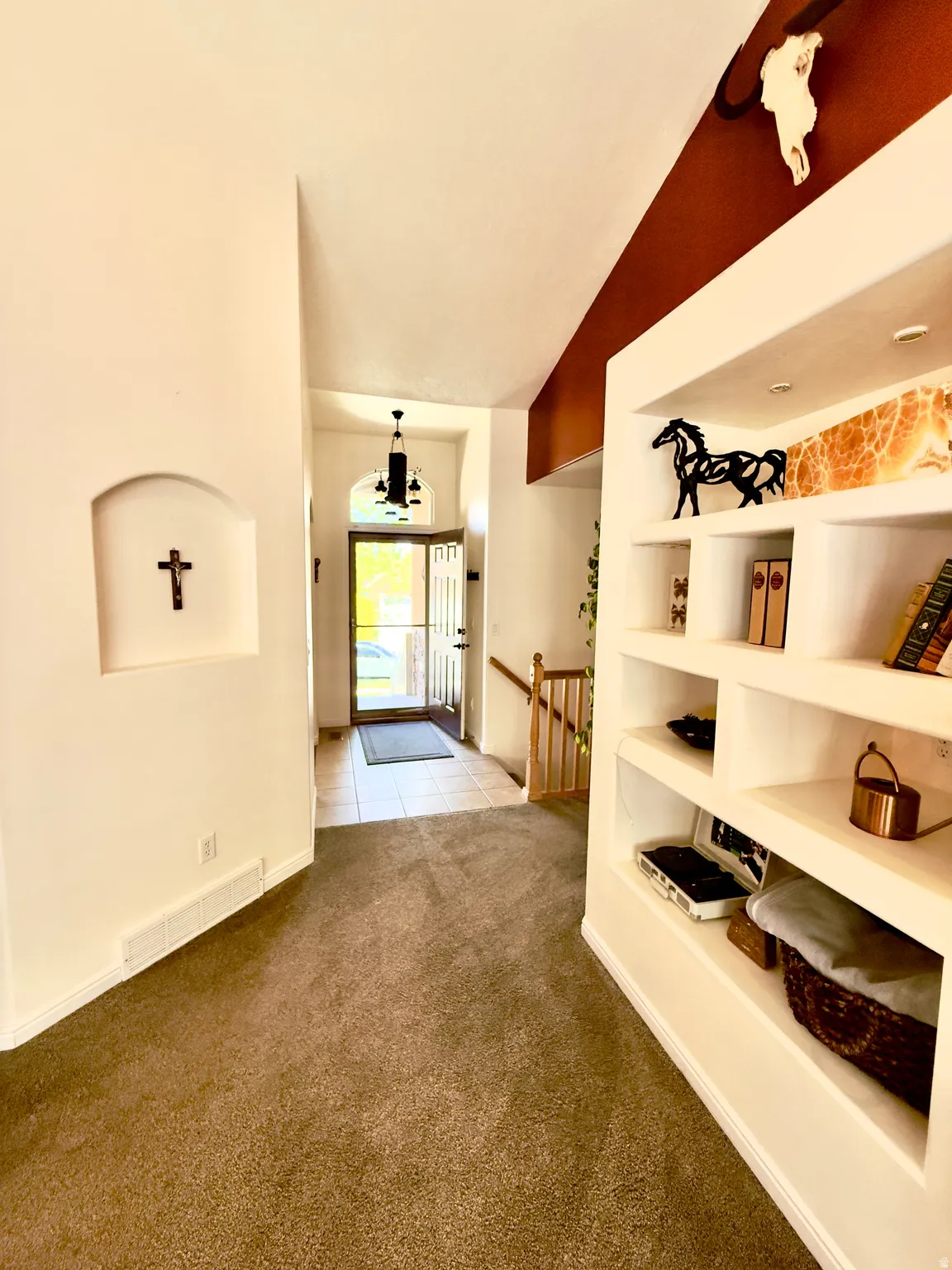 Entryway with light carpet, lofted ceiling, and a chandelier
