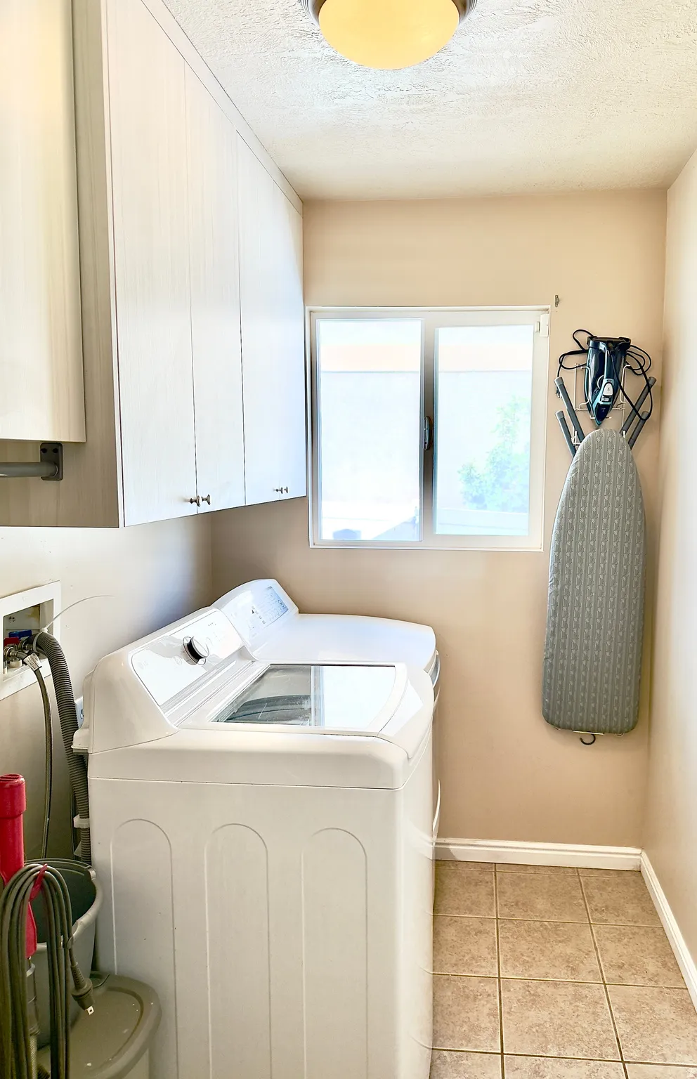 Laundry room featuring light tile patterned floors, a textured ceiling, independent washer and dryer, and cabinet space