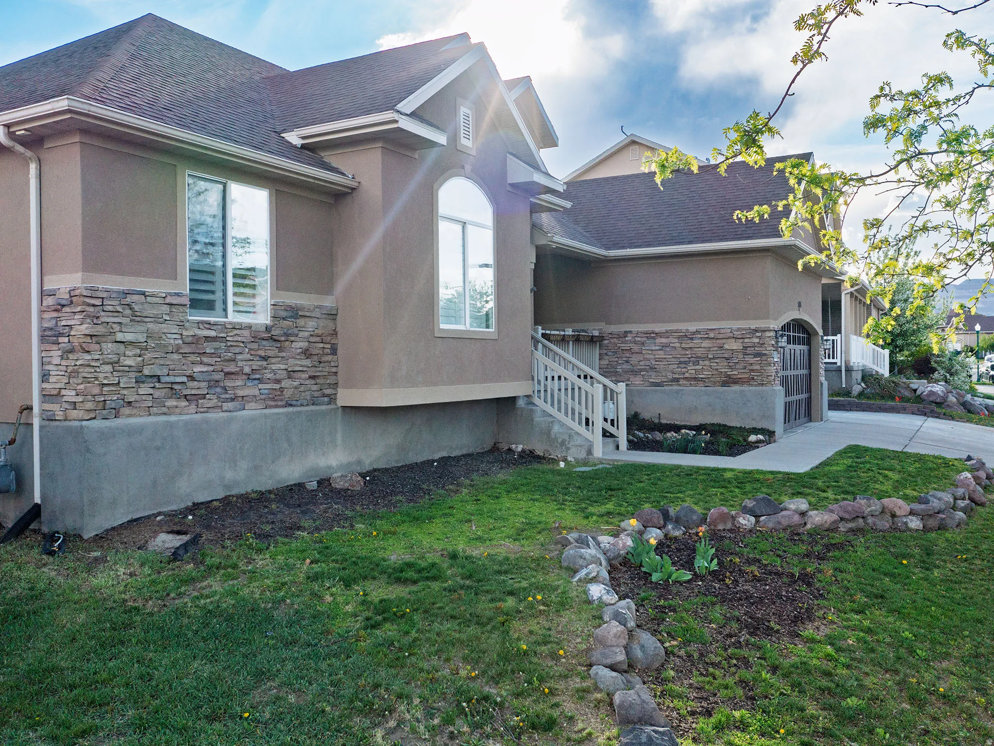 View of side of property featuring stone siding, a yard, stucco siding, and a shingled roof