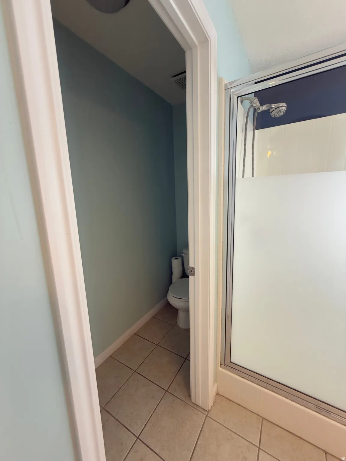 Bathroom with a shower stall and light tile patterned floors