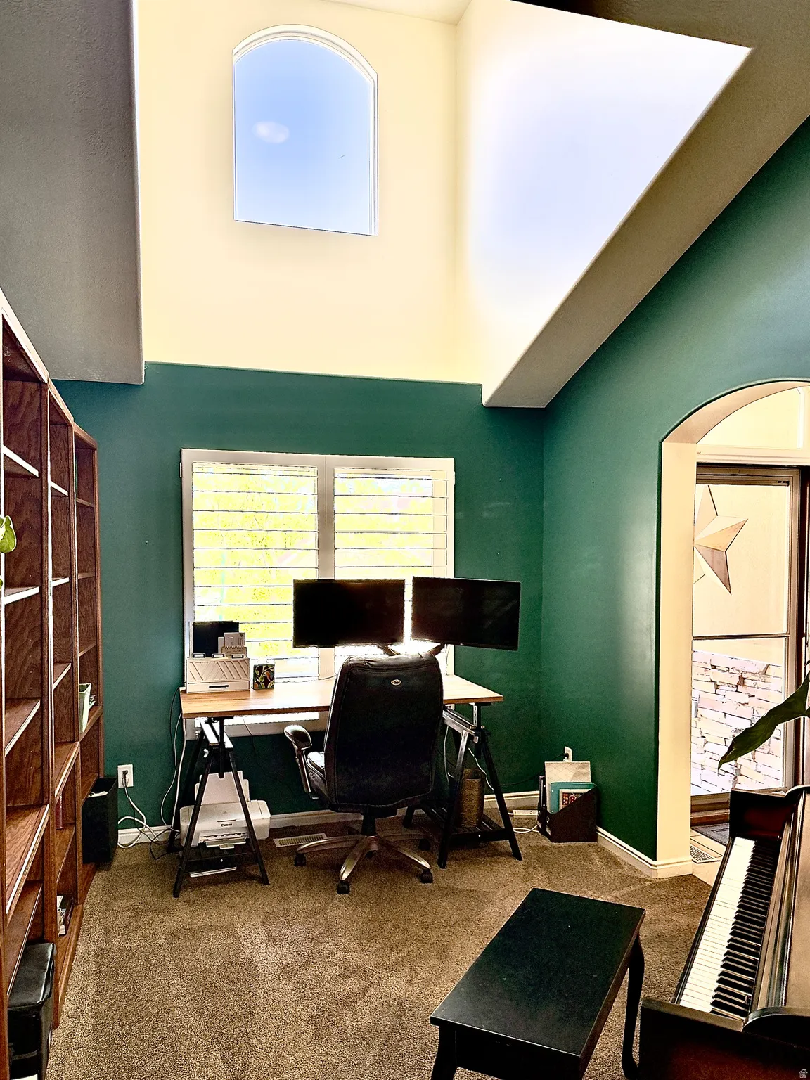 Carpeted office featuring plenty of natural light, a high ceiling, and arched walkways