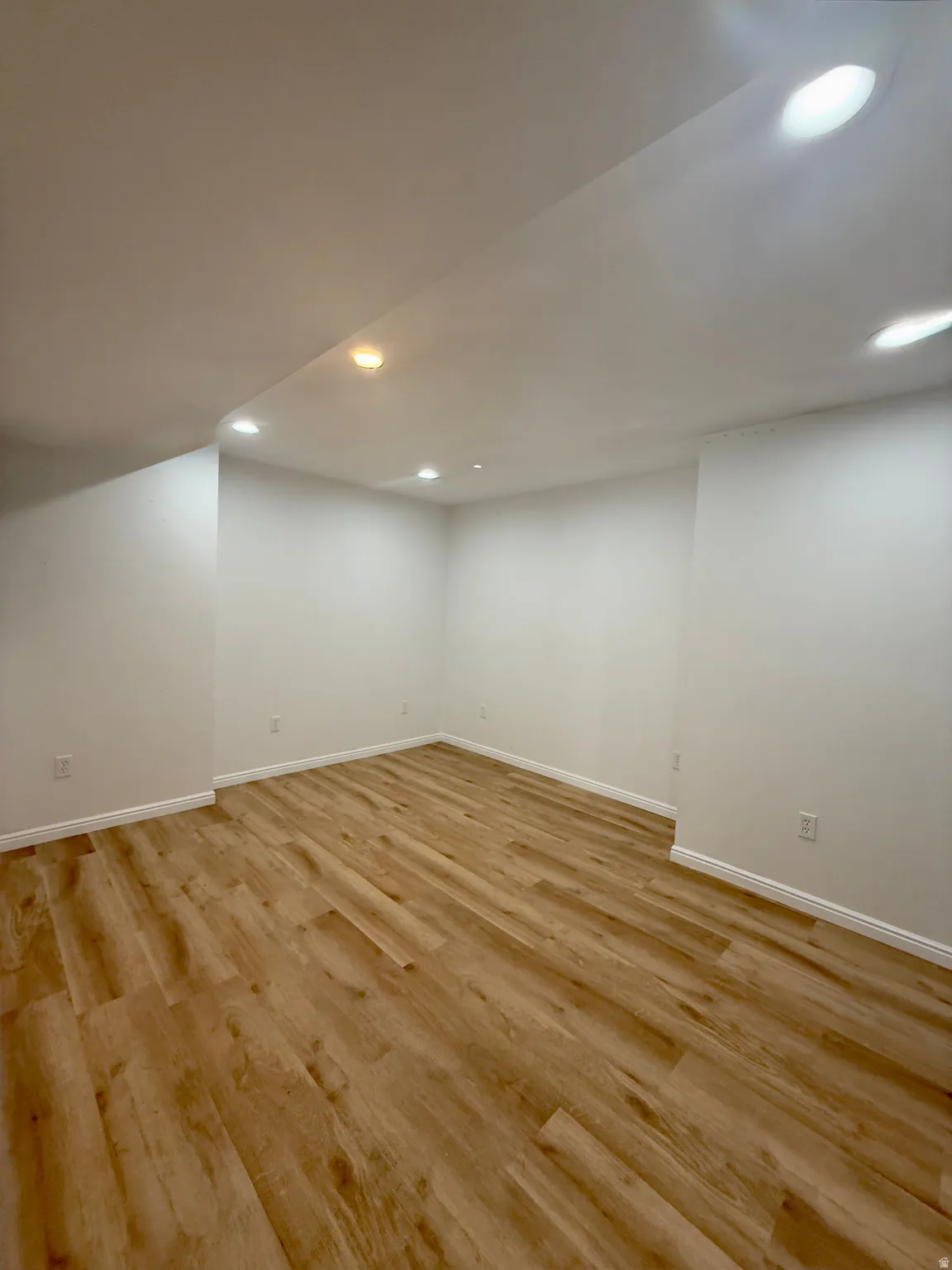 Spacious room featuring wood-finish flooring and recessed lighting