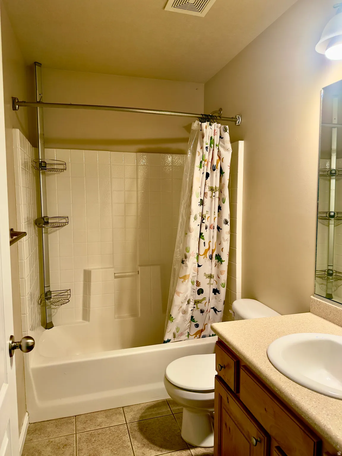Full bathroom featuring a white tub/shower combination with white tiled surround, a white toilet, and a vanity with a light-colored countertop and integrated sink