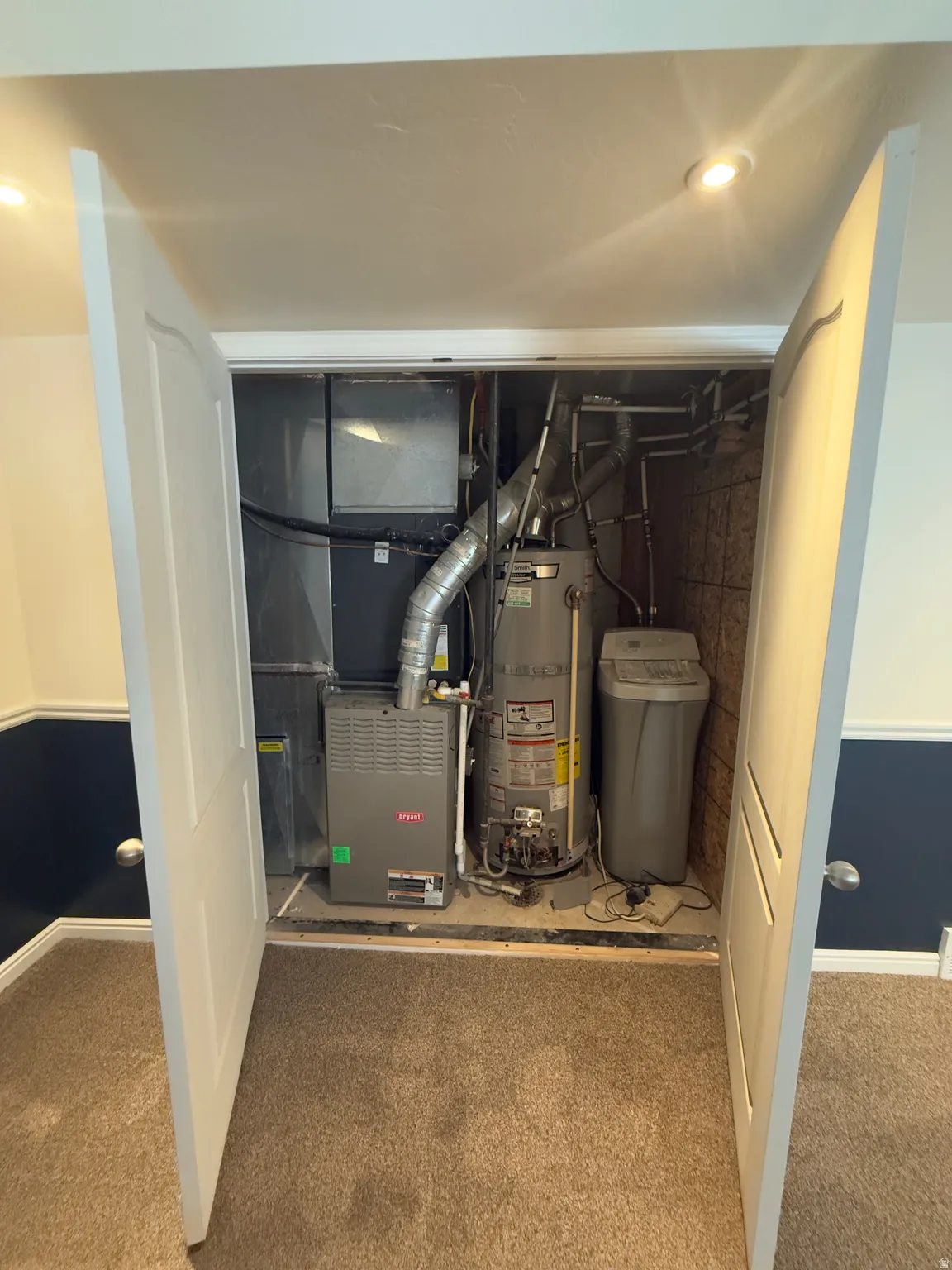 Utility closet featuring a water heater, furnace, and water softener