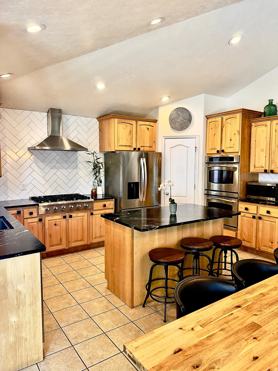 Kitchen with backsplash, stainless steel appliances, a kitchen island, light tile patterned flooring, and a breakfast bar area