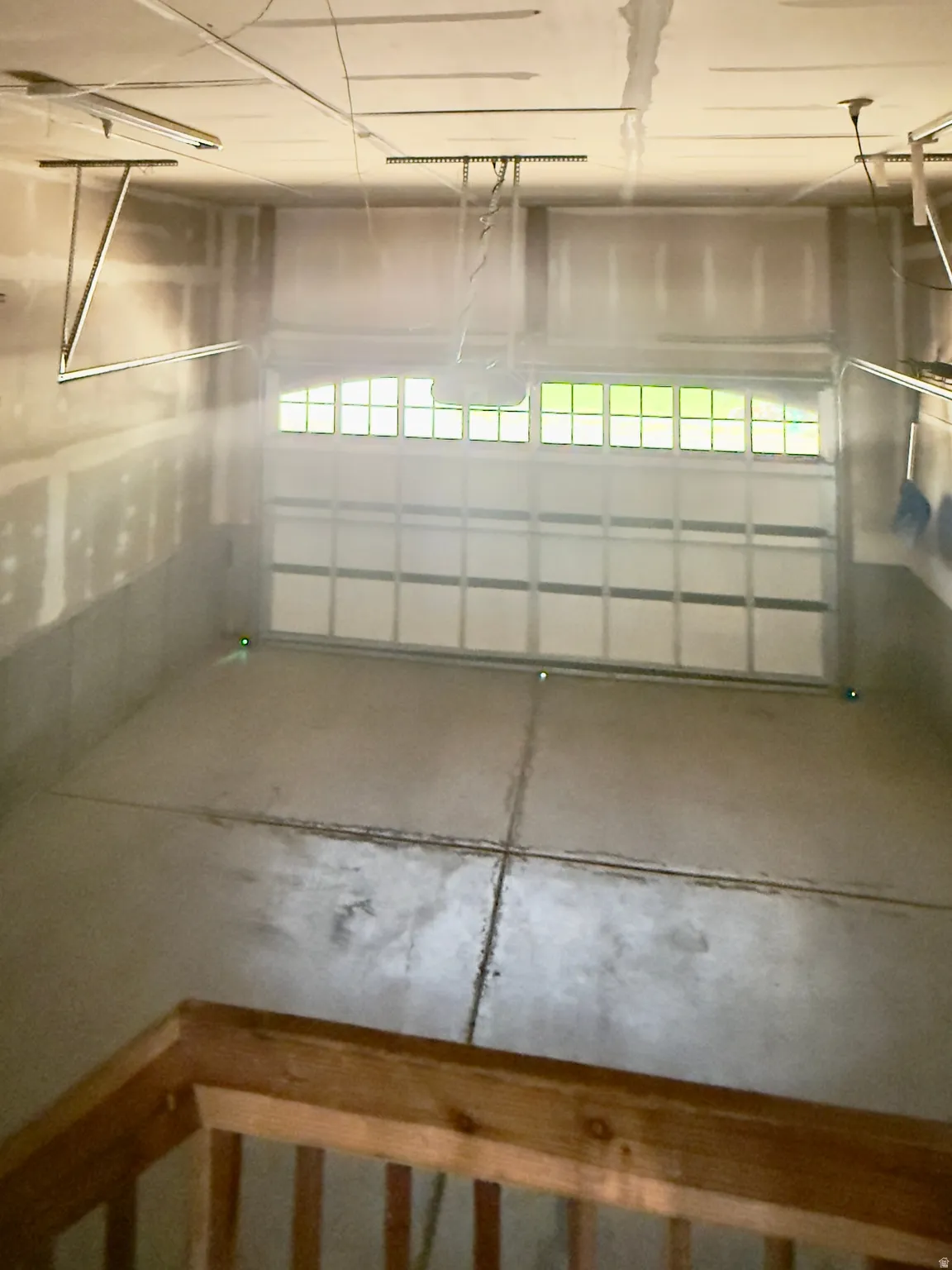 Spacious garage featuring a concrete floor, an overhead garage door with upper-level windows, and an automatic garage door opener