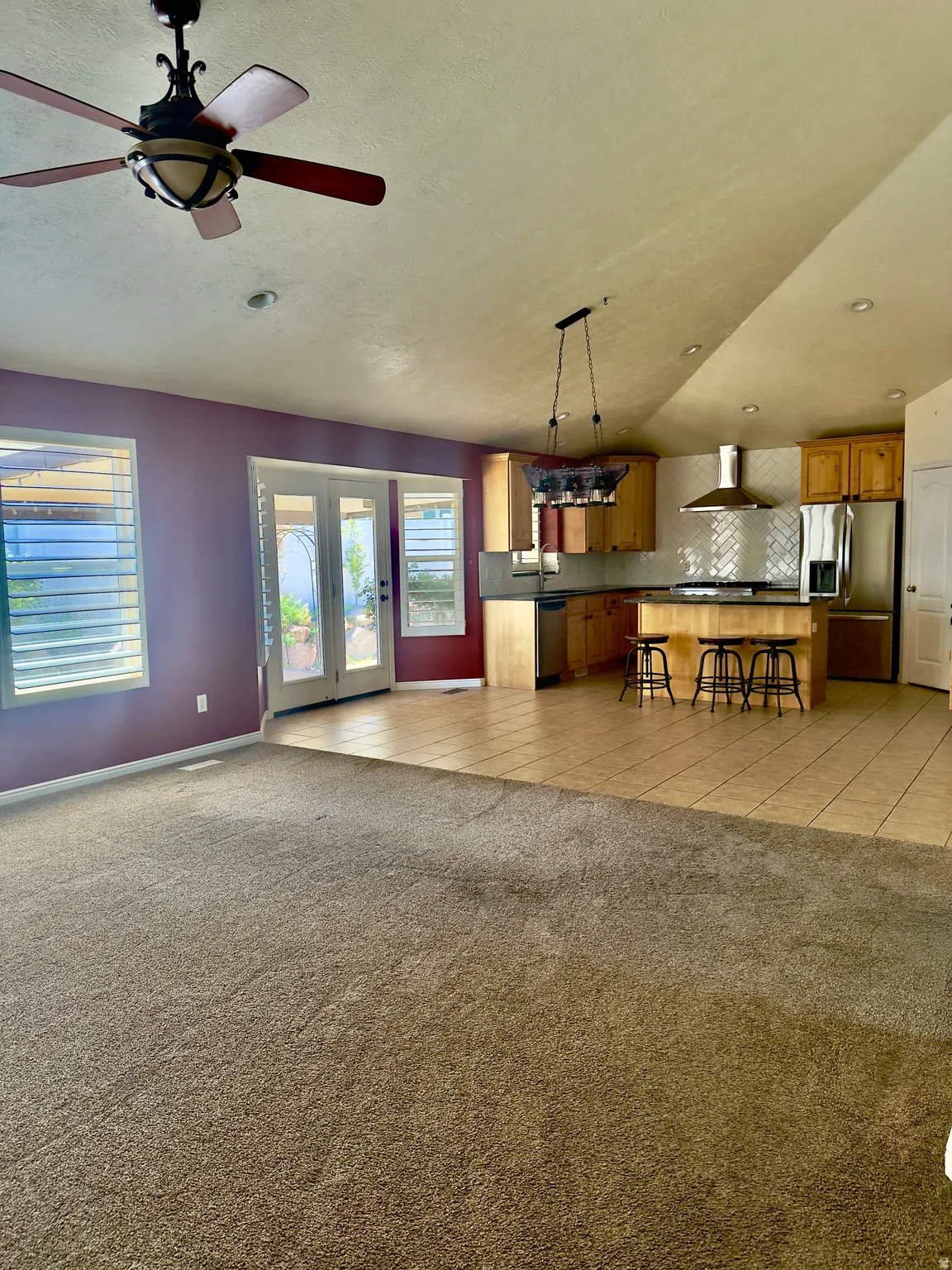 Open-concept living area with carpeted flooring transitioning to tile