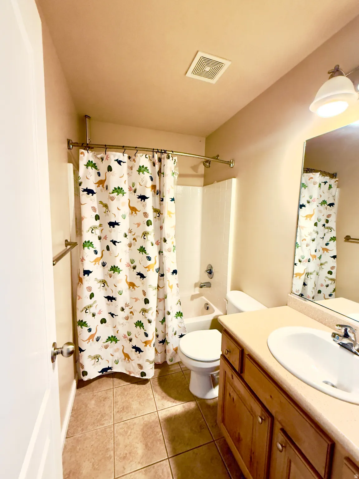 Bathroom featuring vanity, shower / bath combo with shower curtain, and light tile patterned flooring