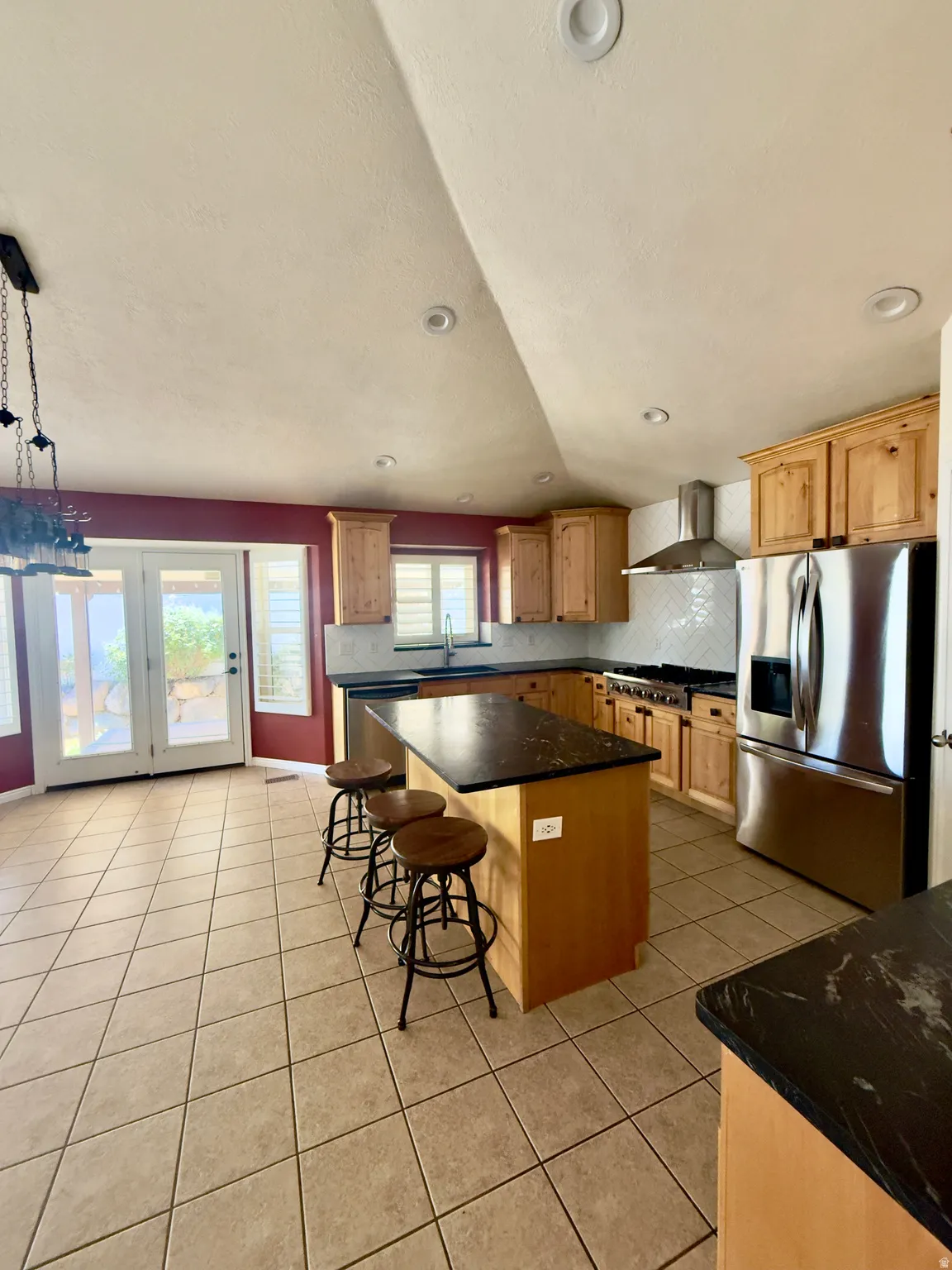 Kitchen featuring light wood cabinetry, dark stone countertops, stainless steel appliances, and a diagonal tile floor
