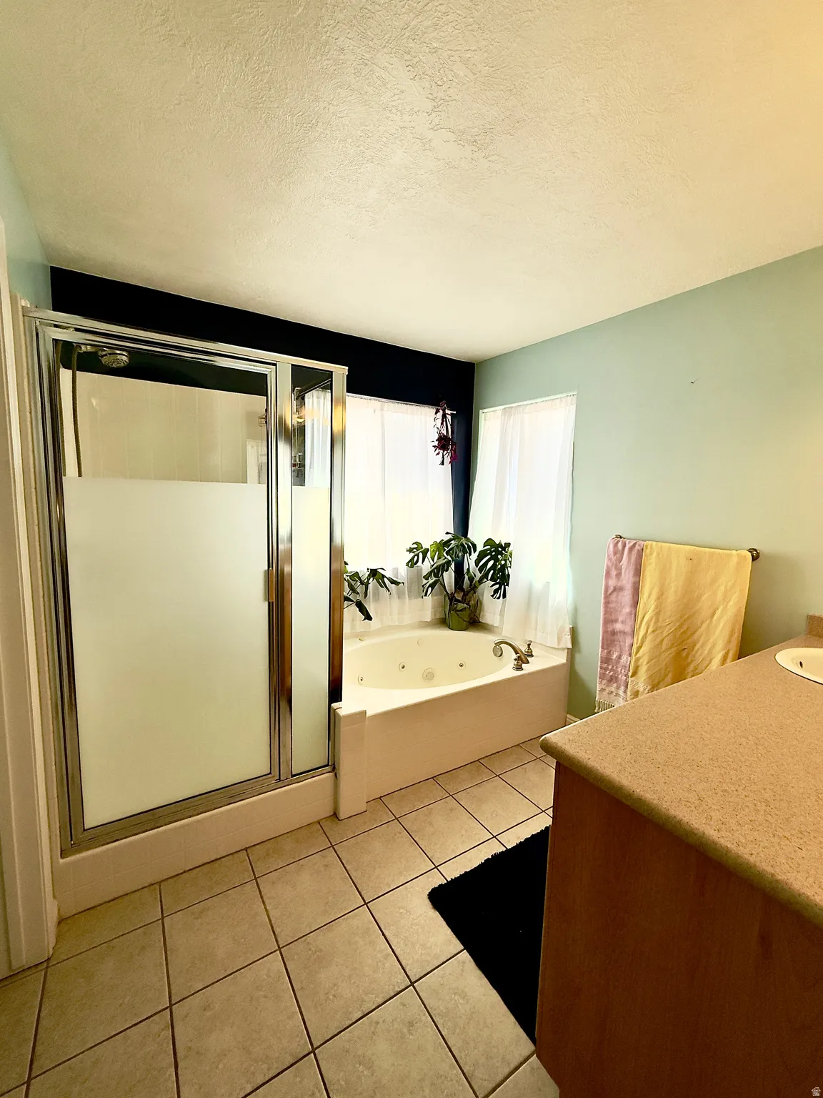 Full bathroom featuring vanity, a textured ceiling, a stall shower, a jetted tub, and light tile patterned floors