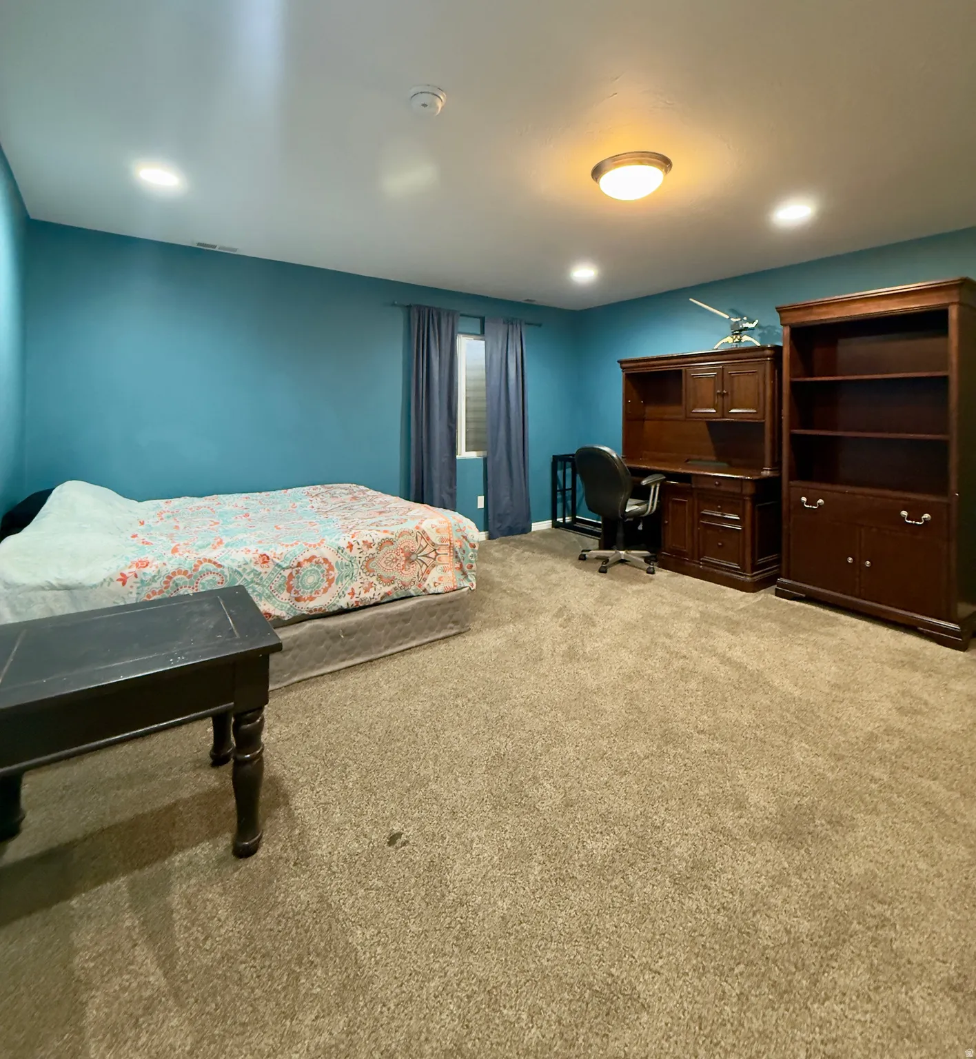 Bedroom featuring light carpet and an office area